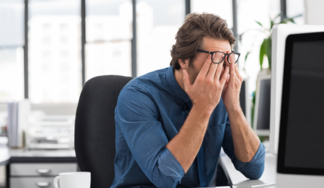 Un homme se frotte les yeux devant son écran.