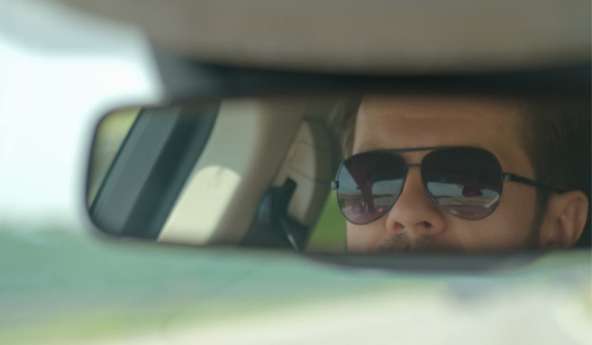 Un homme équipé de lunettes de soleil conduit.