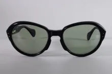 Paire de lunettes d’AUDREY HEPBURN en acétate teinté noir, les verres teintés vert. L'intérieur de la branche droite gravé en lettres blanches : « Audrey Hepburn ». Signée Pierre Marly.