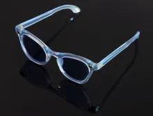 Paire de lunettes de MARLÈNE DIETRICH en acétate teinté bleu pâle, soulignée de rosaces en métal au niveau des charnières.