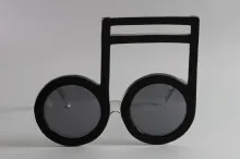 Paire de lunettes d’ELTON JOHN, en forme de notes de musique, en acétate teinté noir, les branches translucides en partie pailletées gris. L'intérieur de la branche droite gravé en lettres blanches : « Elton John ».