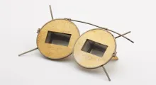 Lunettes de lit, acétate et métal, milieu du XXe siècle. Dotées d’un prisme à 60° ou 90° degrés, elles permettent à son porteur de voir selon ce même angle sans baisser sa tête. La publicité vante les mérites de ces montures pour les personnes alitées qui peuvent ainsi lire, manger, regarder la télévision sans se tordre le cou ! ©Musée de la Lunette - coll. Essilor-Pierre Marly. Photo : Pierre Guénat